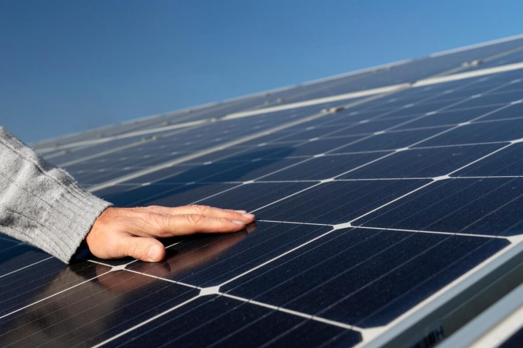 Una mano acariciando un panel solar fotovoltaico